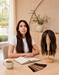 Consulta personalizada de The Hair Collective: asesora sentada a la mesa junto a una peluca sobre un soporte y un set de muestras de color de cabello
