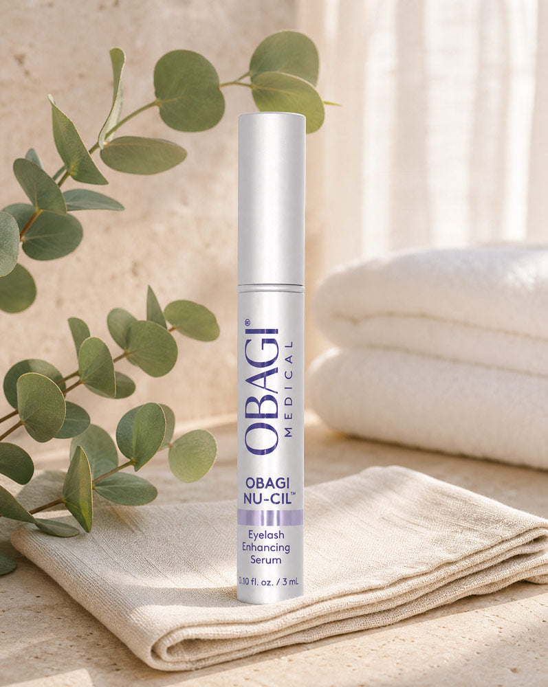 Obagi Nu-Cil Sérum Potenciador de Pestañas de pie sobre servilleta de lino con eucalipto